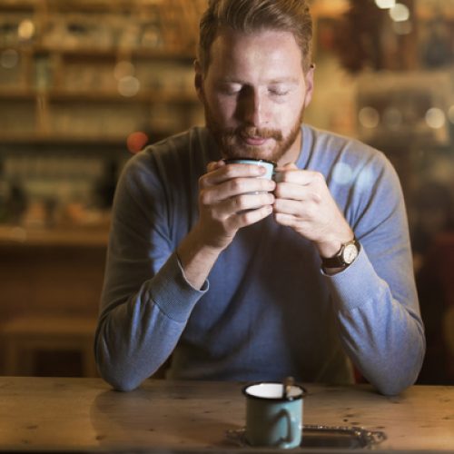 Young handsome man drinking coffee in bar alone